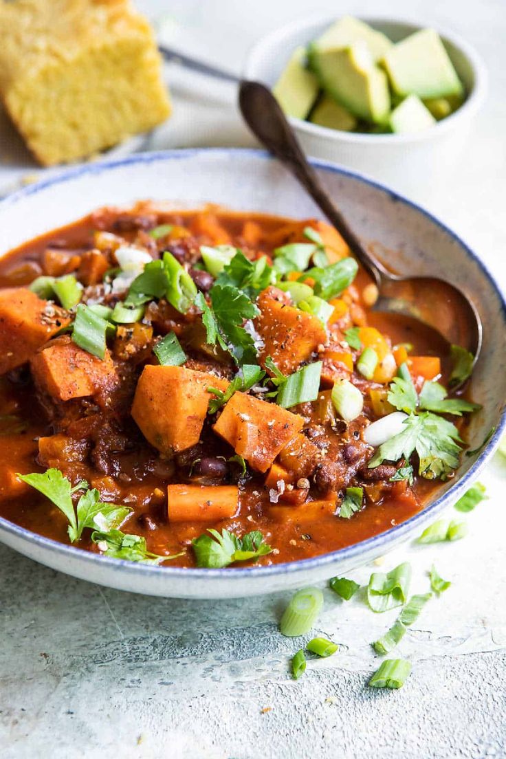 a bowl filled with chili and tofu next to bread