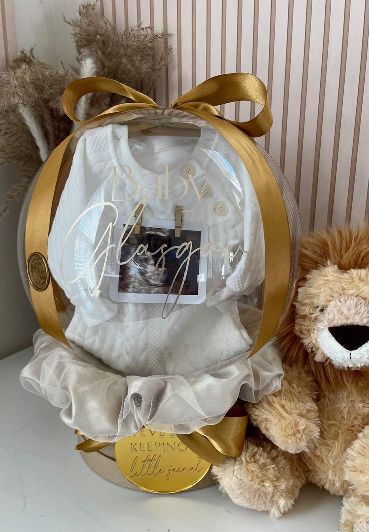 a teddy bear sitting next to a gift bag with a baby's photo on it