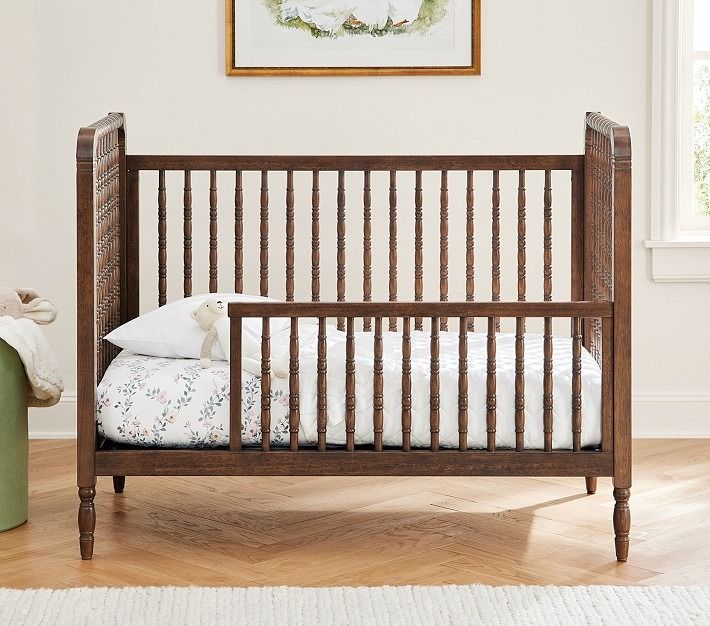 a baby crib in the corner of a room with a painting on the wall