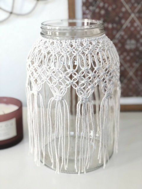 a glass jar sitting on top of a white table next to a candle holder with beads