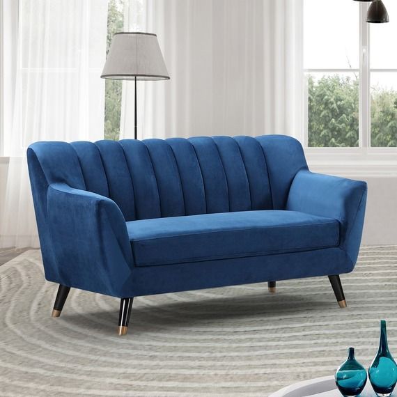 a blue couch sitting on top of a rug in a living room next to a window