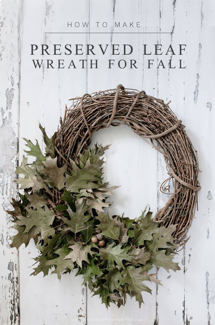 a wreath is hung on the side of a white door with leaves and berries around it