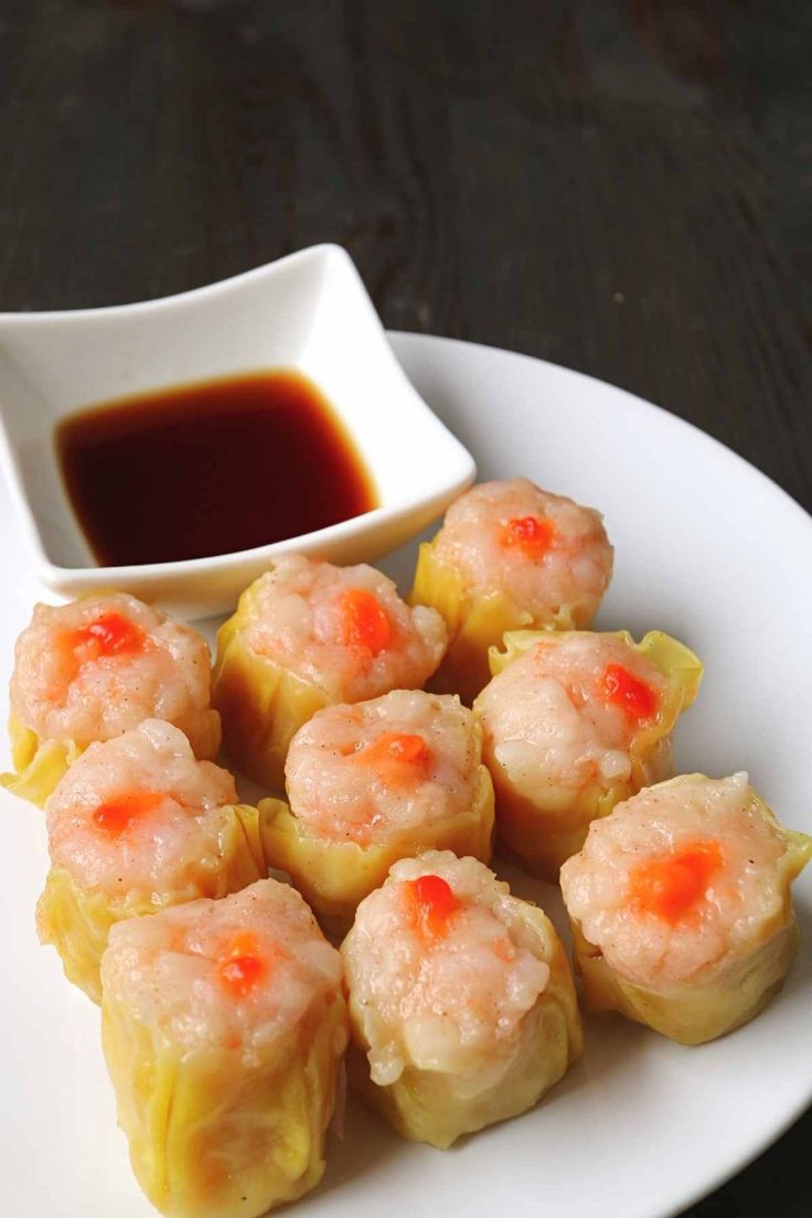 some food is sitting on a white plate with dipping sauce in the bowl next to it