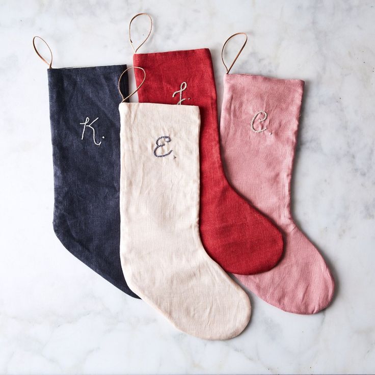 three stockings with monogramming on them sitting on a marble countertop next to each other