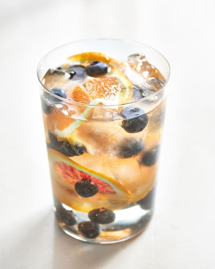 a glass filled with fruit and ice on top of a table