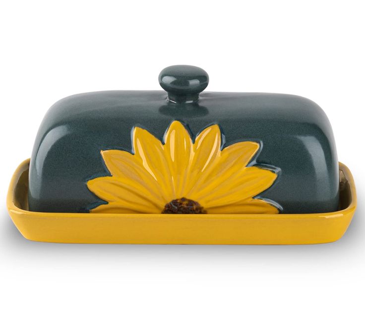 a yellow and green dish with a flower on the bottom, sitting in front of a white background