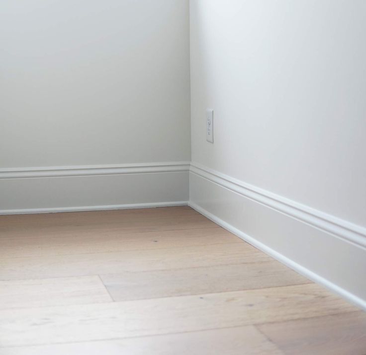 an empty room with white walls and wood floors