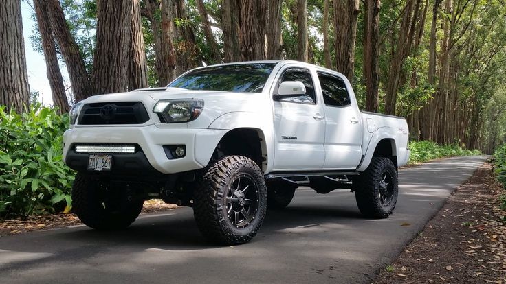 a white truck is parked on the side of the road in front of some trees