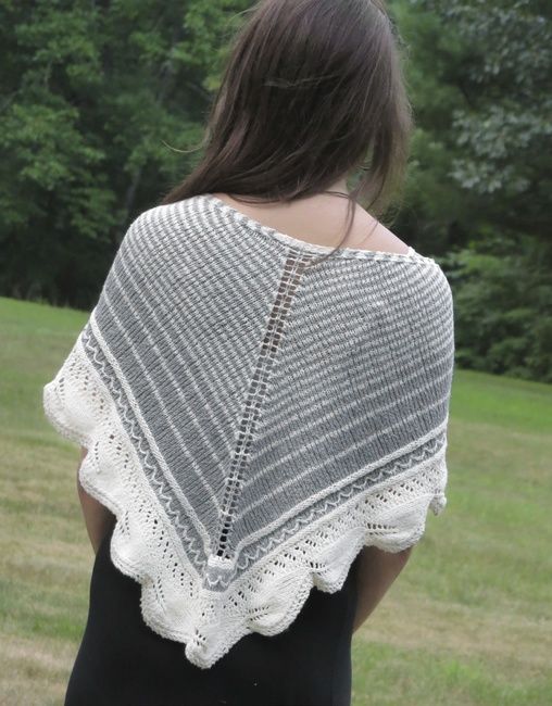 a woman wearing a white crochet shawl in front of some grass and trees