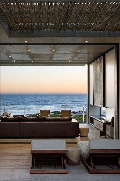 a living room with couches and tables near the ocean