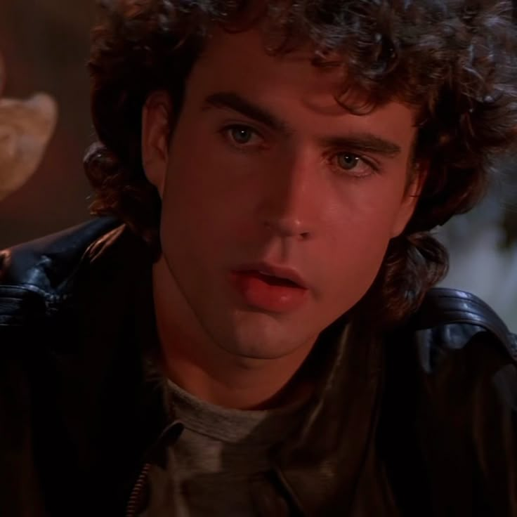 a man with curly hair wearing a leather jacket