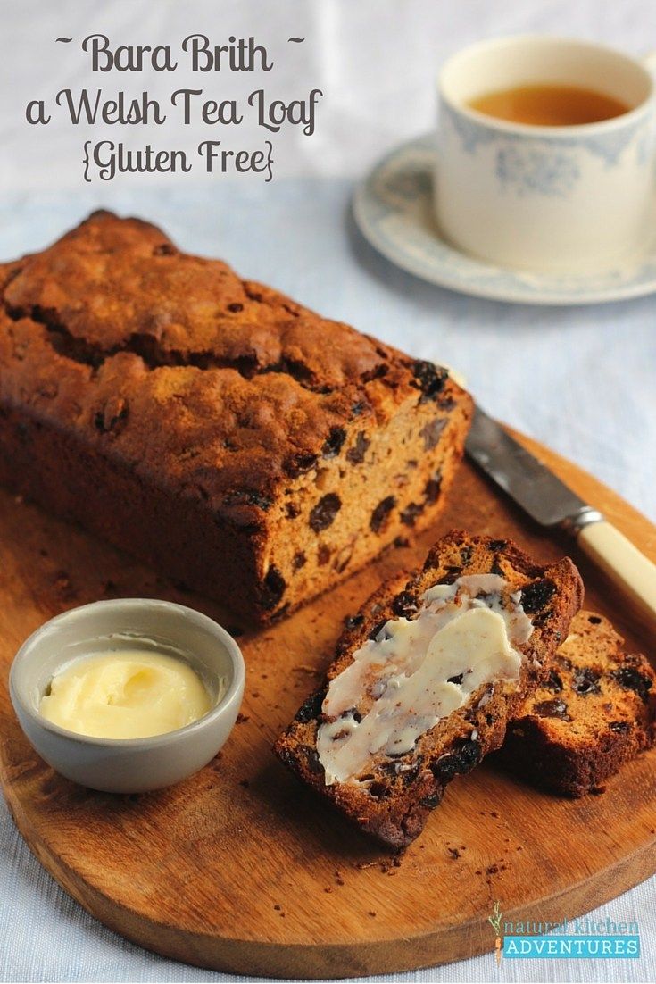 a loaf of bread sitting on top of a wooden cutting board next to a cup of tea