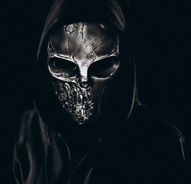 a man wearing a hoodie with a skull on it's face in the dark