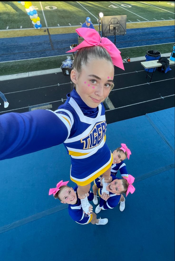 a cheerleader is posing for a photo while holding onto her pom poms