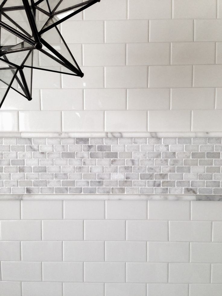 a white tiled wall and ceiling in a room with black fixtures hanging from the ceiling