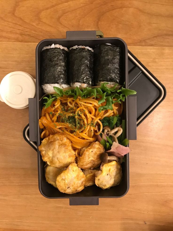 a bento box filled with different types of food on top of a wooden table