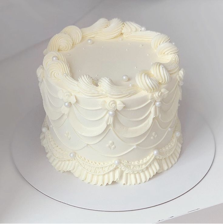 a close up of a white cake on a plate with icing and pearls around the edges