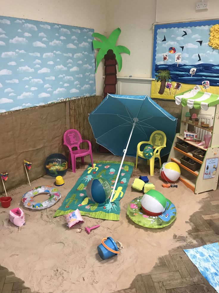 there is an umbrella and other toys in the playroom with sand on the floor