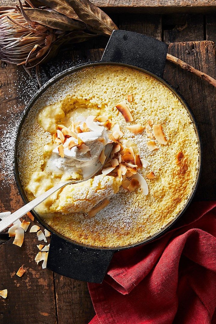 a skillet filled with food on top of a wooden table next to a red napkin