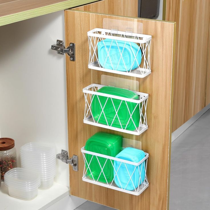 three baskets are hanging on the wall in front of a kitchen counter top with dishes and cups