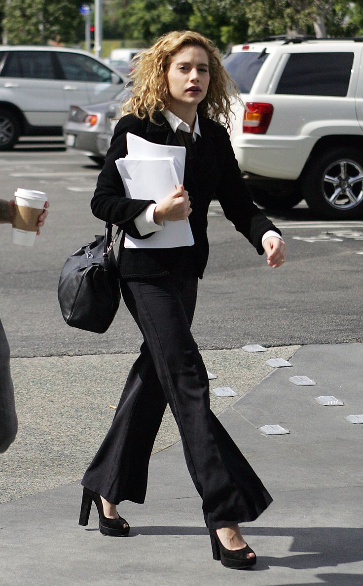 a woman is walking down the street carrying papers