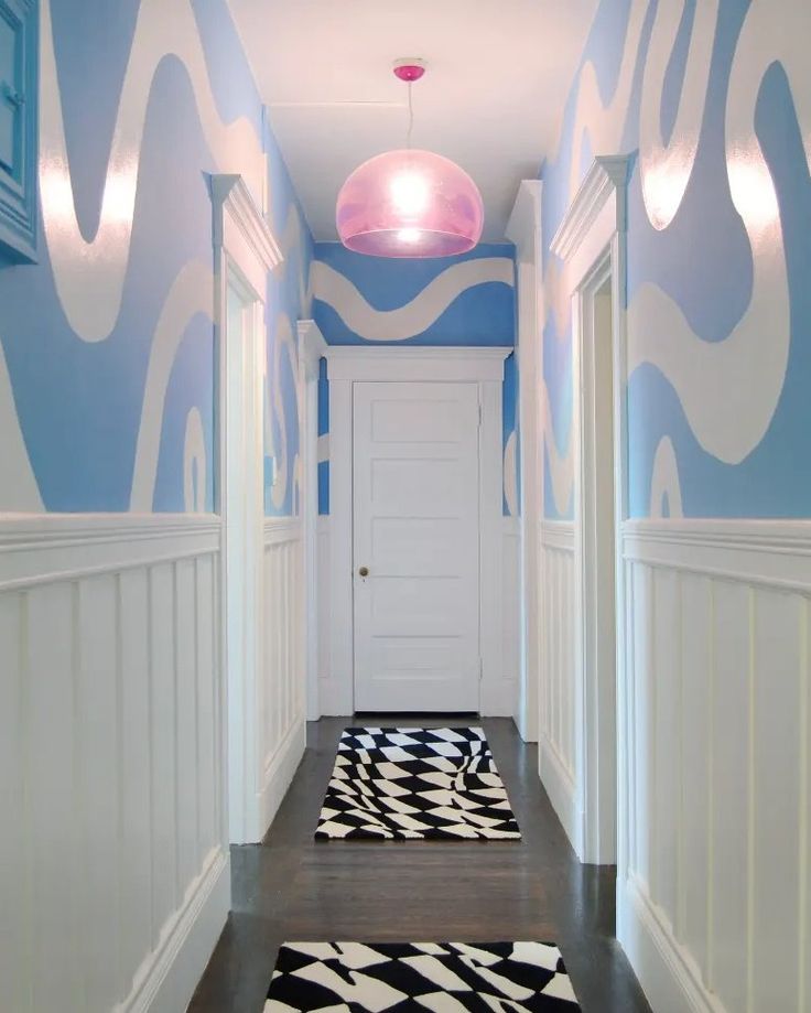 a hallway painted in blue and white with black and white rugs on the floor