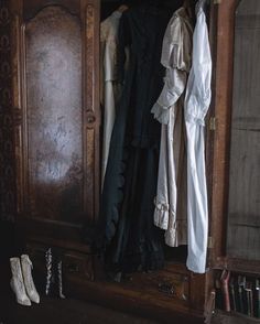 an old wooden wardrobe with clothes hanging on it