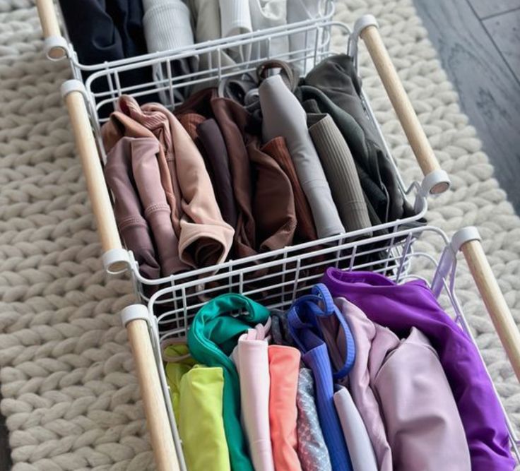 a basket filled with lots of different types of clothes on top of a carpeted floor