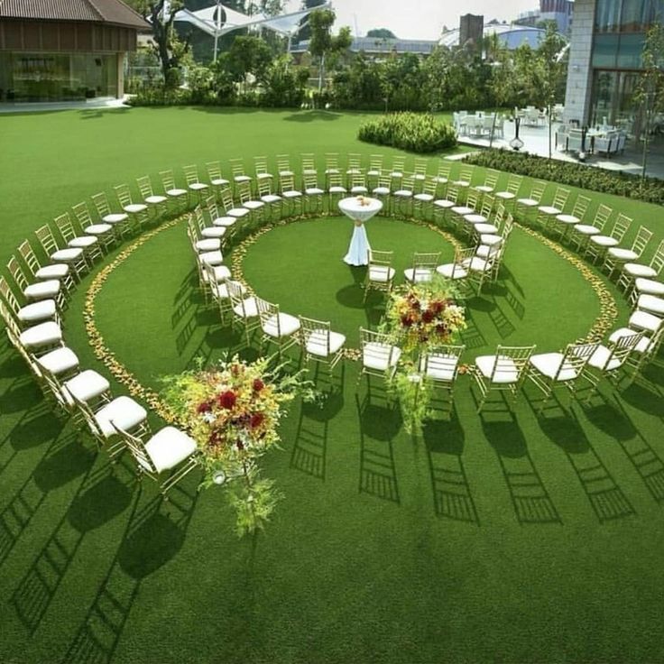 a circular lawn with chairs and flowers in the center