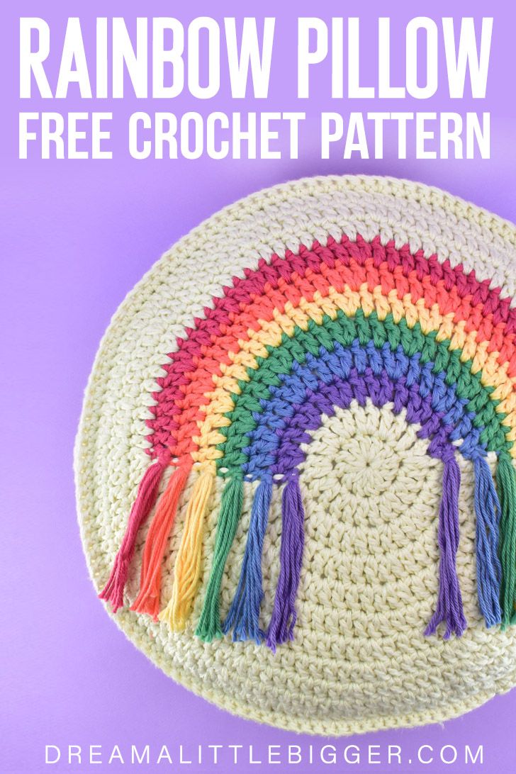 a crocheted rainbow pillow with tassels on it and text overlay that reads, rainbow pillow free crochet pattern