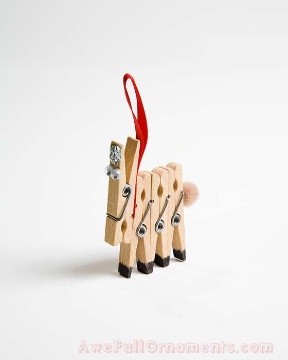 four wooden pegs in the shape of sheep with a red ribbon hanging from it's back