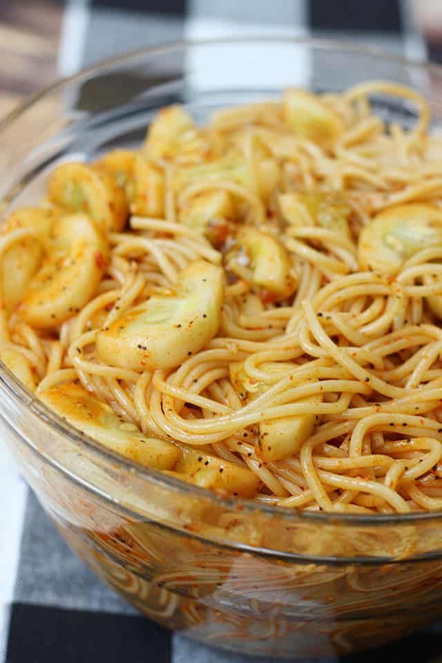 a glass bowl filled with pasta and bananas on top of a checkered table cloth