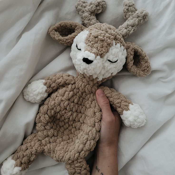 a person is holding a stuffed animal in bed