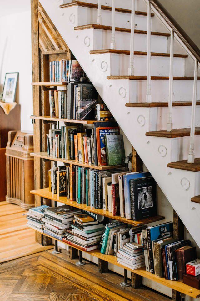 a bookshelf filled with lots of books next to a stair case