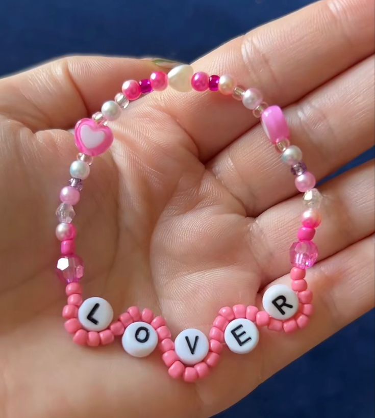 a hand holding a beaded bracelet with the word love spelled in letters on it