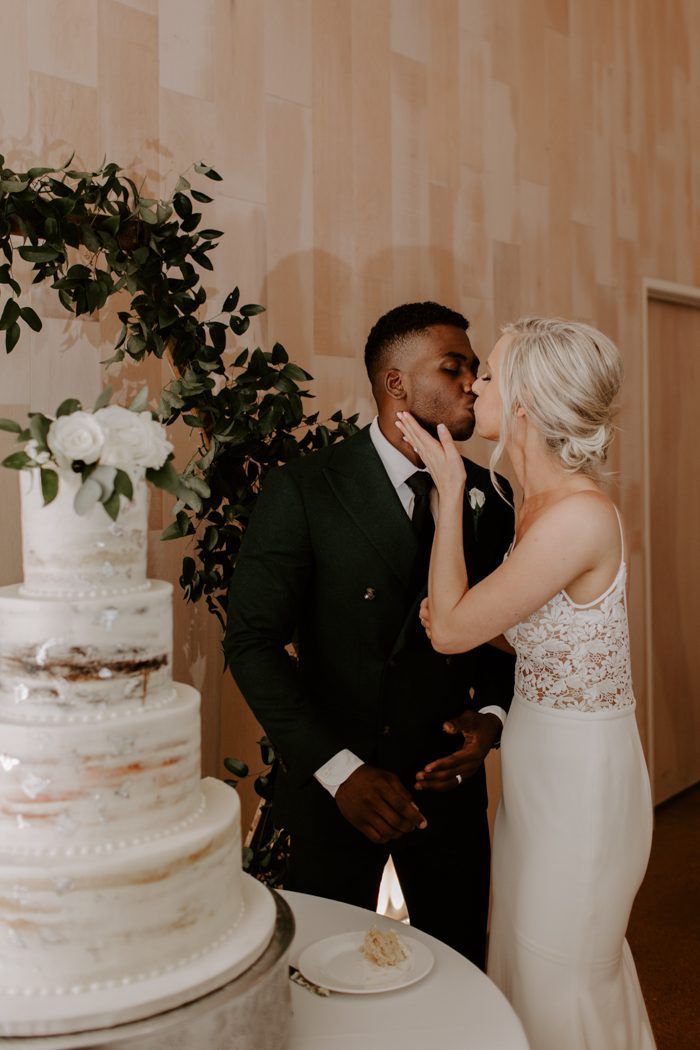 a bride and groom kissing in front of a wedding cake