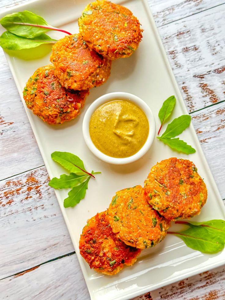 three crab cakes on a plate with dipping sauce