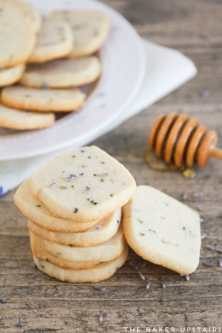 a stack of shortbread cookies next to a plate of honeycomb cookies on a wooden table