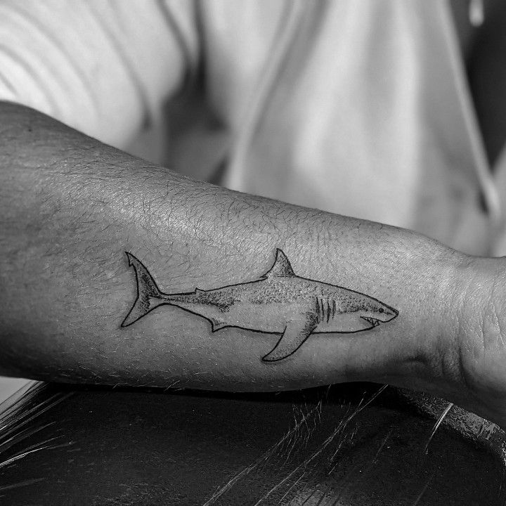 a black and white photo of a man's arm with a shark tattoo on it