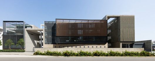 the building has many windows on it and is made out of metal, with plants growing in front