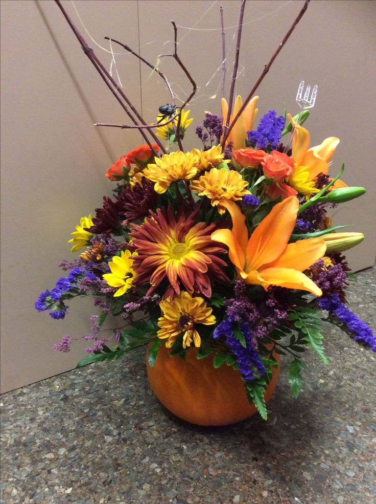 a vase filled with lots of colorful flowers on top of a stone counter next to a wall