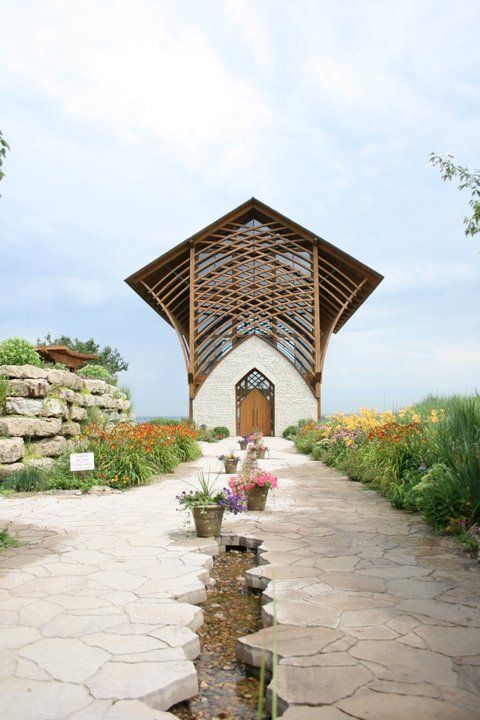 an outdoor chapel with flowers in the foreground and water running through the walkway on either side