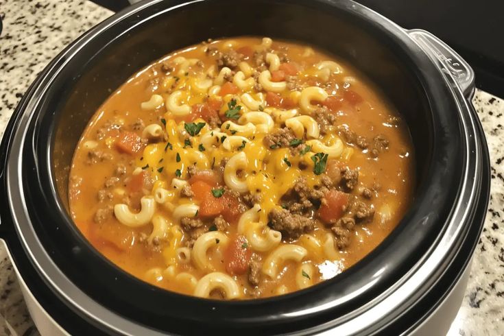 a crock pot filled with macaroni and cheese soup on top of a table