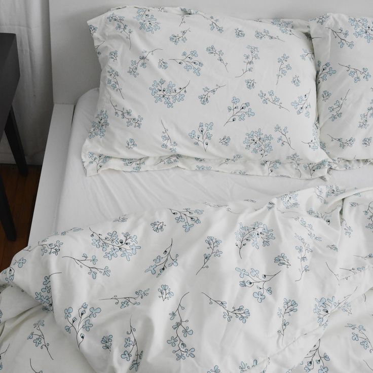 an unmade bed with blue flowers on it