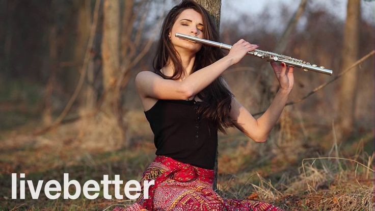 a woman sitting on the ground with a flute in her hand