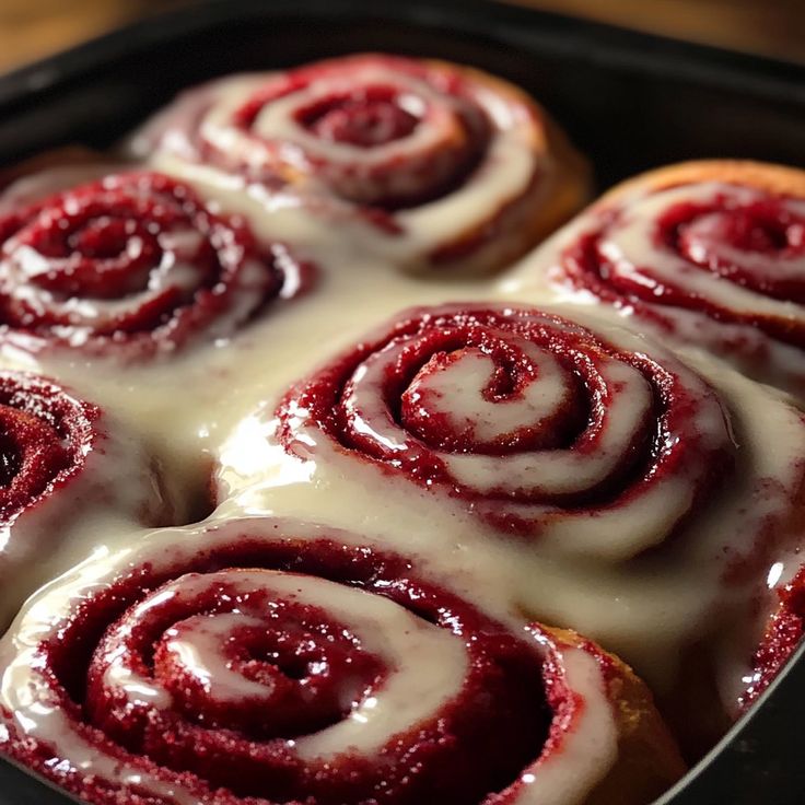 a pan filled with cinnamon rolls covered in glaze and drizzled with icing