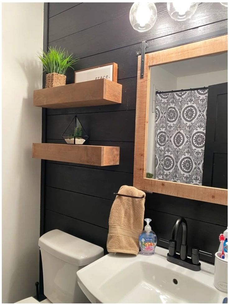 a white toilet sitting under a bathroom mirror next to a wooden shelf filled with items