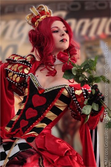 a woman with red hair wearing a costume and holding a rose in her hand while standing next to a sign