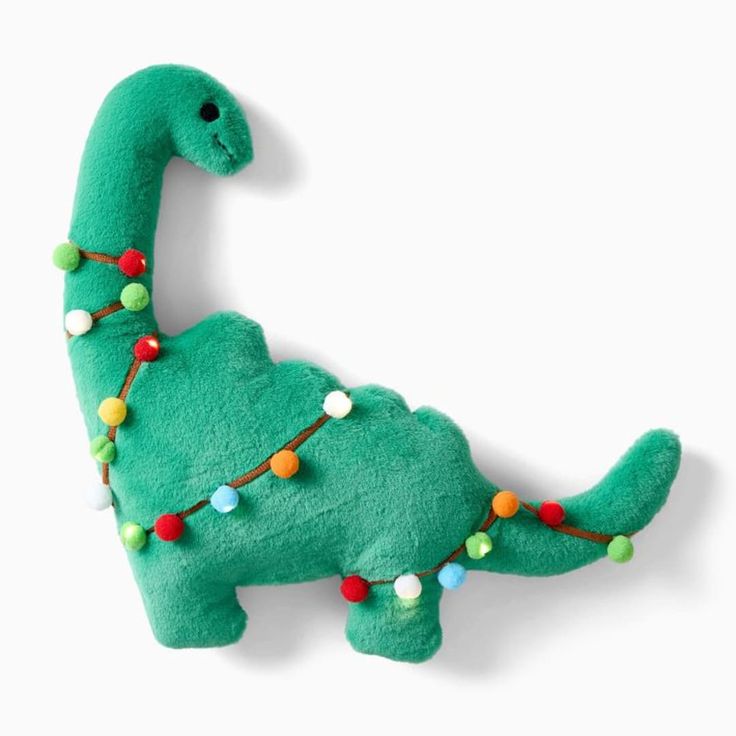 a green dinosaur stuffed animal with christmas lights on it's head and neck, sitting against a white background