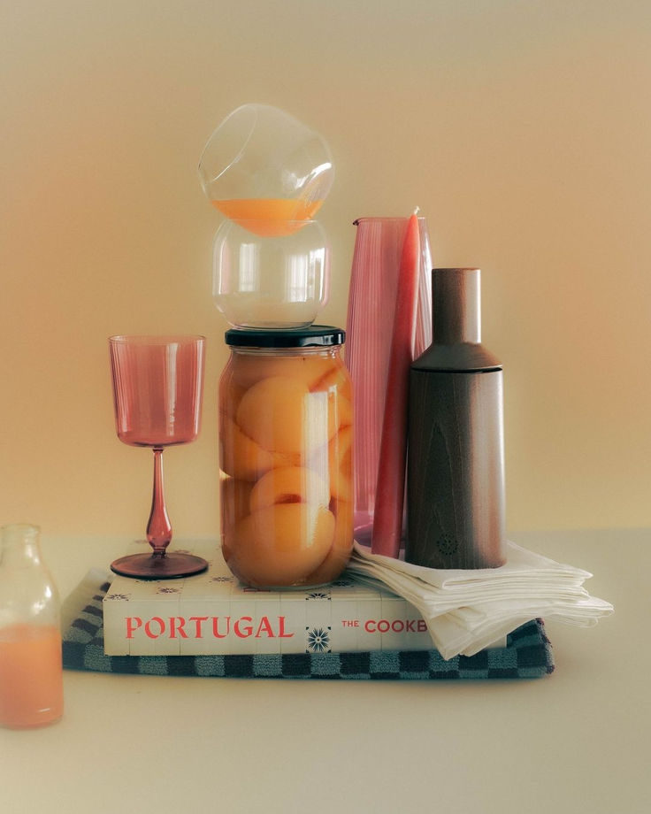 a jar filled with liquid sitting on top of a book next to a glass cup